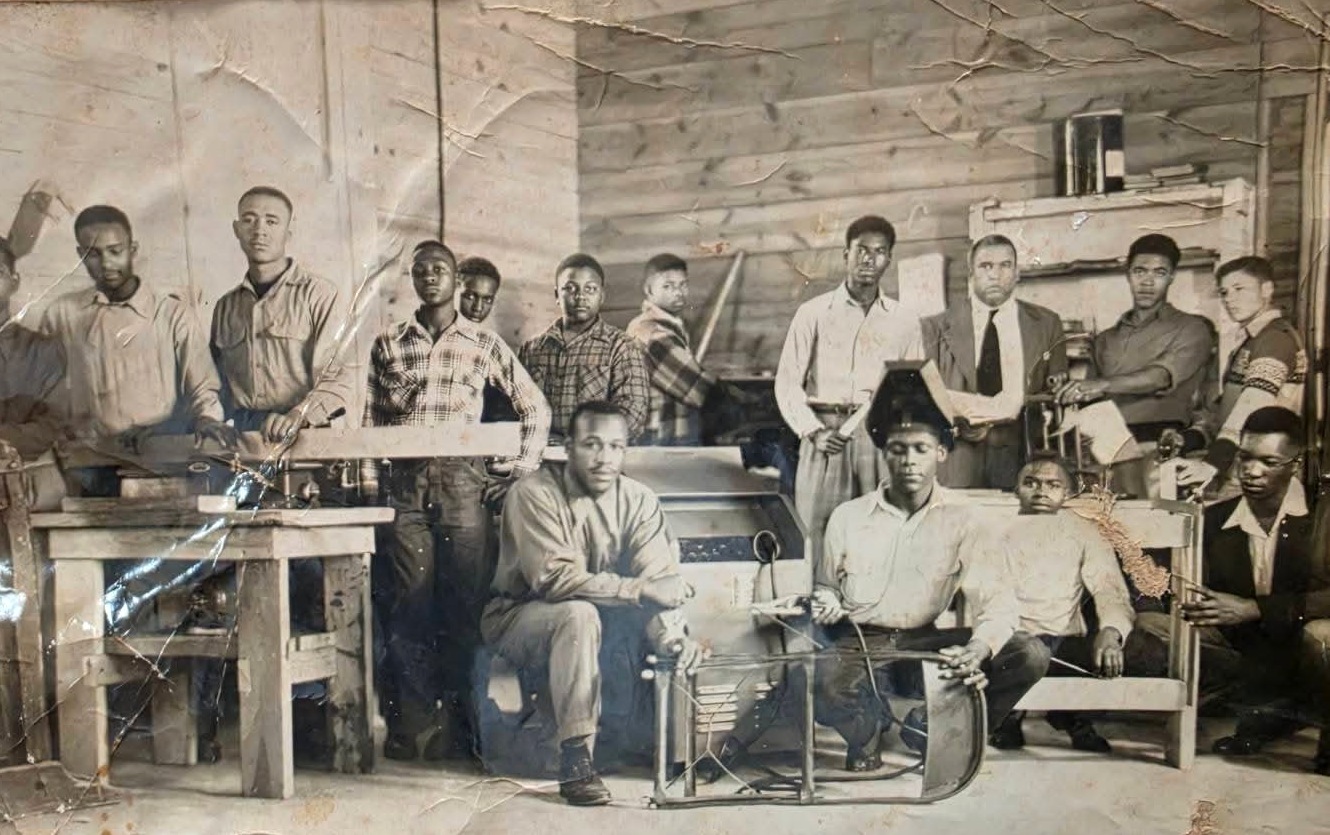 Archival photograph of a vocational shop class of young men with tools and workbenches